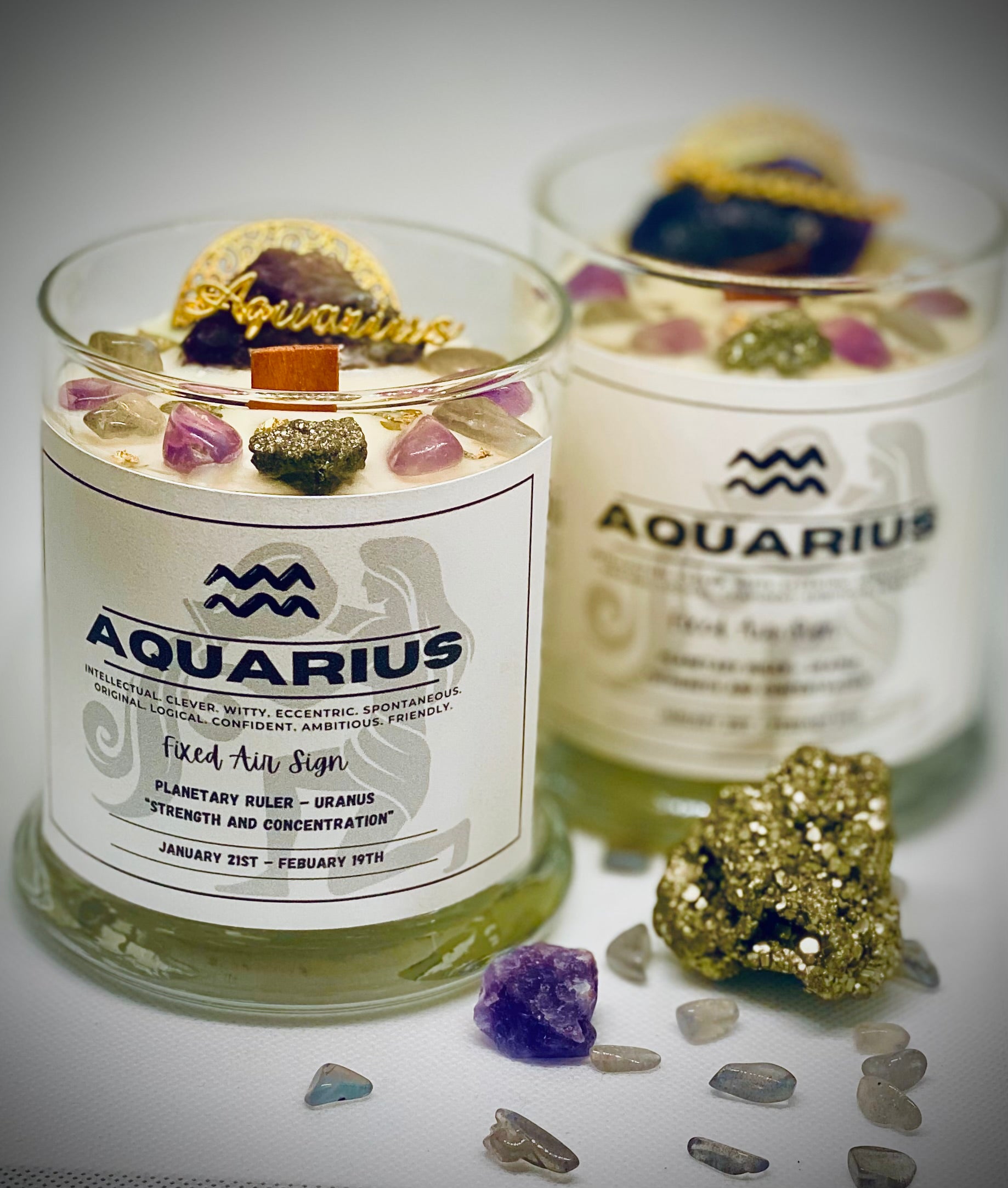 Two candles labeled 'Aquarius' with decorative elements on a reflective surface.